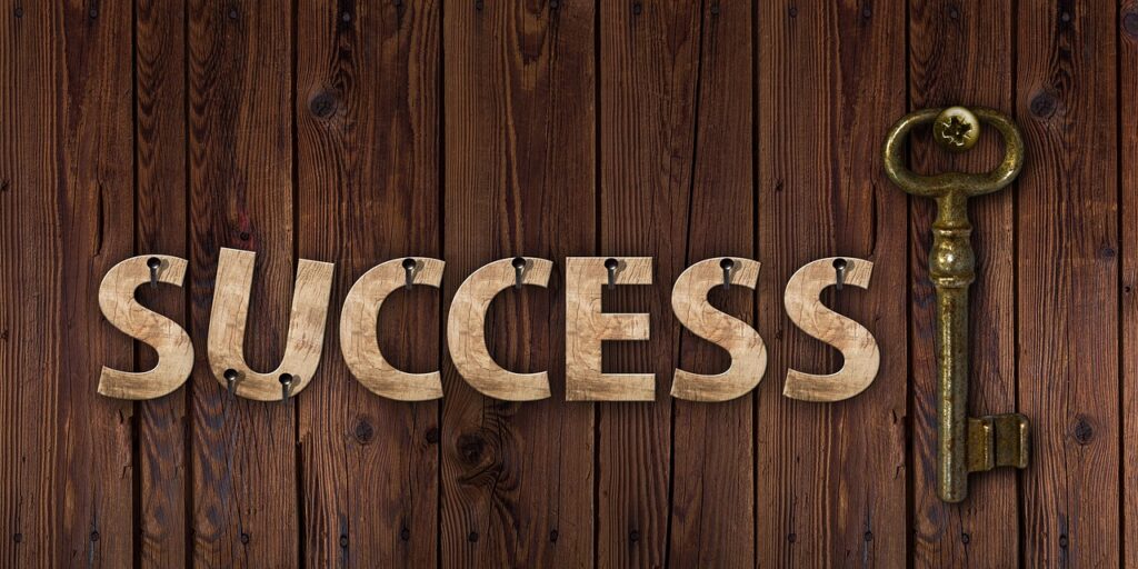 Photo of a key next to the word Success against a wooden background