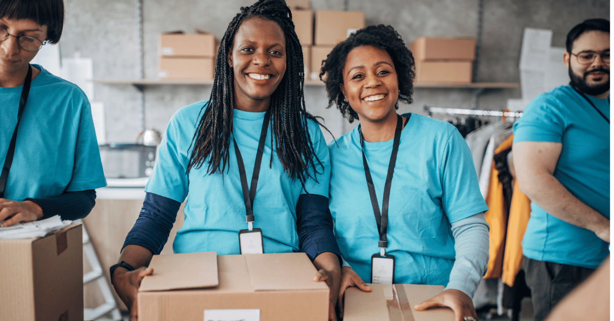 Photo of four volunteers at a donation center smiling while holding boxes