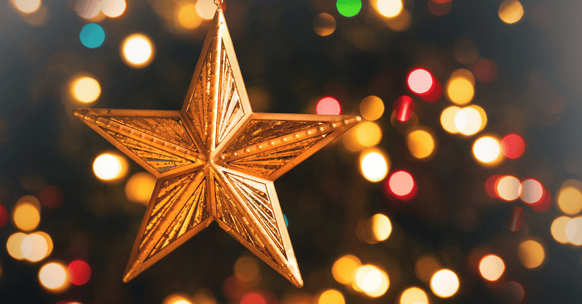 Photo of a gold star ornament on a tree with Christmas lights