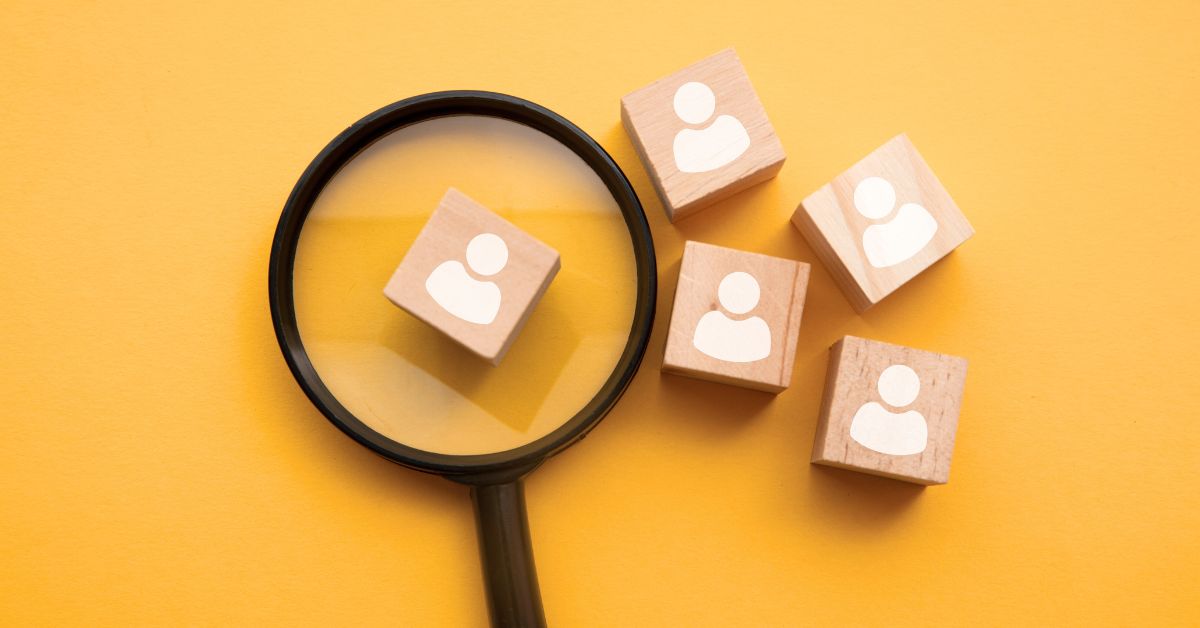 Graphic of a magnifying glass over wooden blocks with a person icon