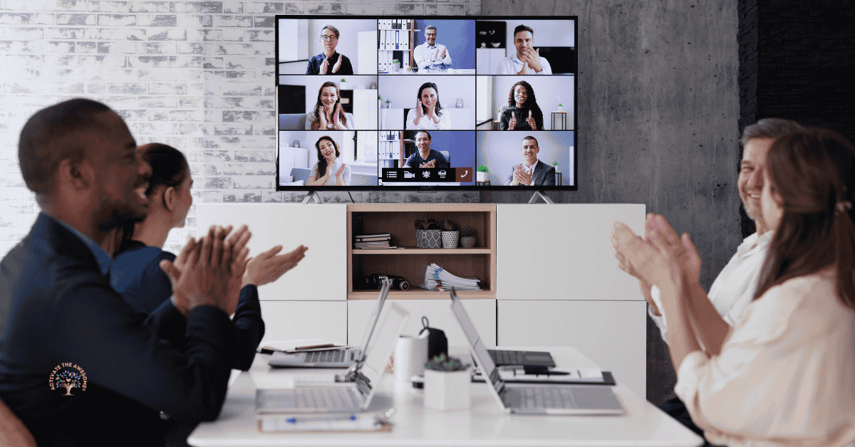 Hybrid team meeting with in-office employees applauding while remote coworkers join on a video conference screen.