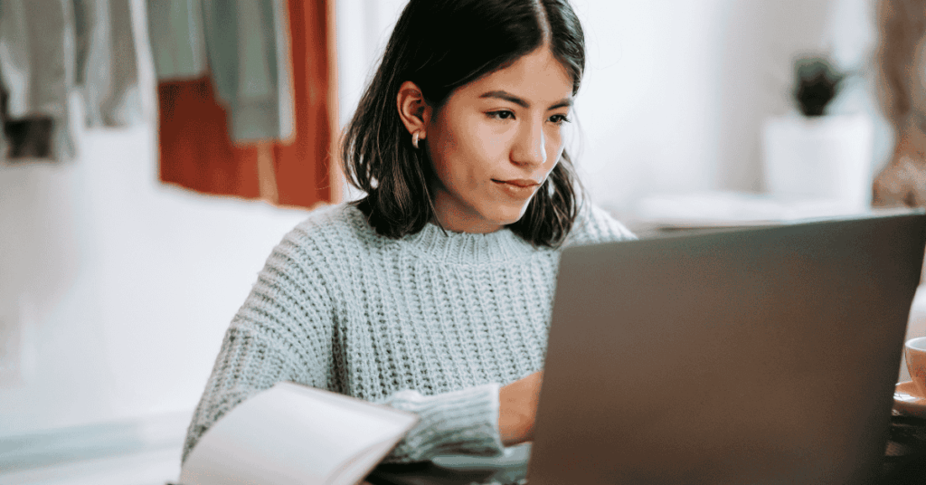 Young woman working remotely on a laptop at home, looking serious and focused, representing remote work isolation